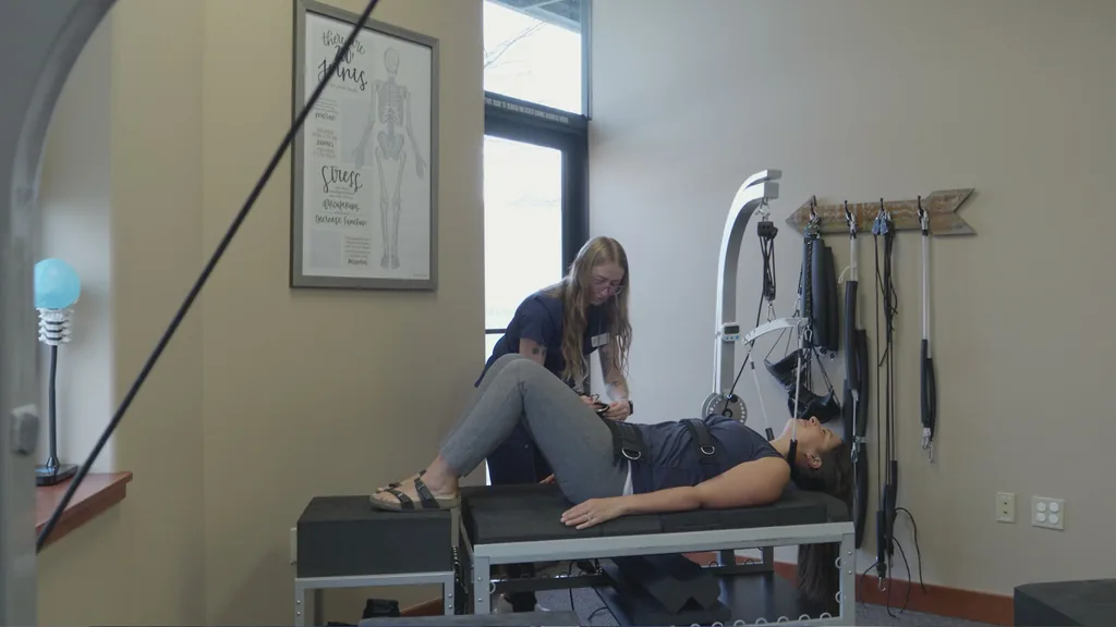 A staff member fits a harness on a patient lying on the clinic's decompression table