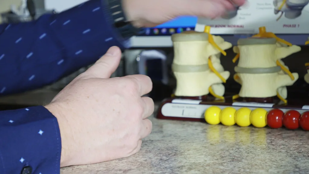 A provider shows a spine model to explain how pressure builds on a disc