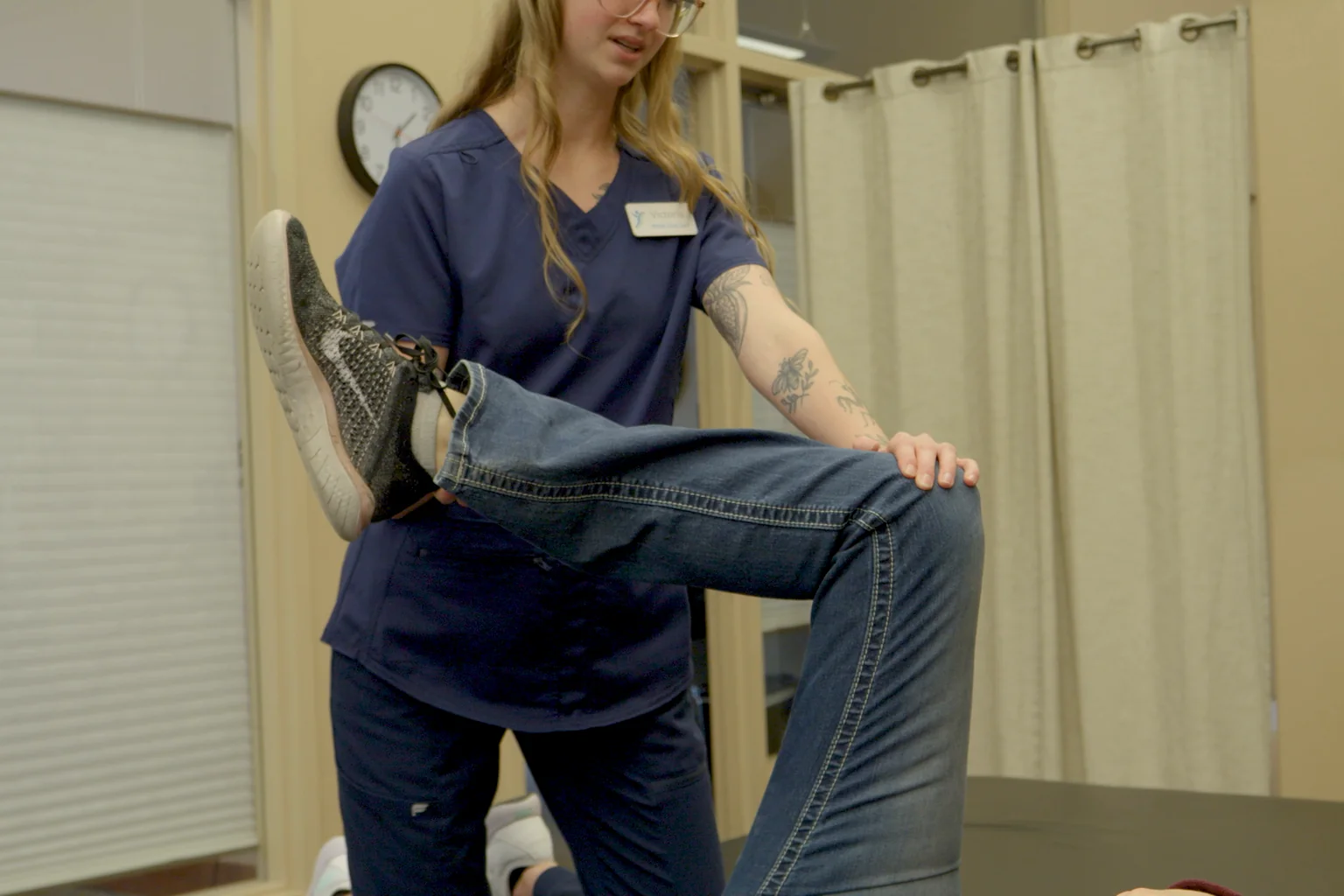 A team member guides a patient through a leg stretch during a rehab session at Advanced Pain Solutions