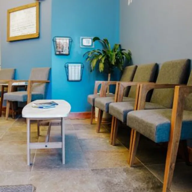 The APS waiting room with a teal accent wall, upholstered chairs and a small table